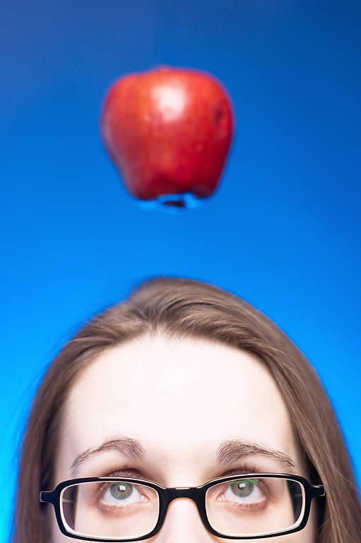 Caucasian woman face with glasses with apple hanging over her